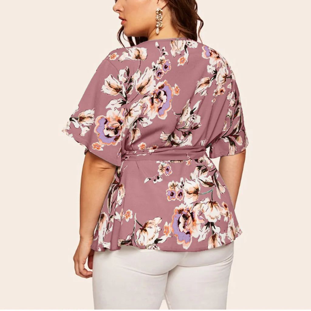 Frau in lila Blumenbluse, Kurzarm, Gürtel, weiße Hose, modisch, elegant, Plus-Size-Mode.