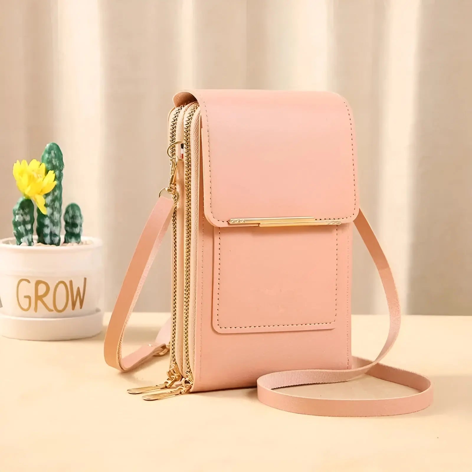 Rosa Leder-Handytasche mit Schulterriemen, modisch, elegant, Damen-Accessoire, neben Kaktus.