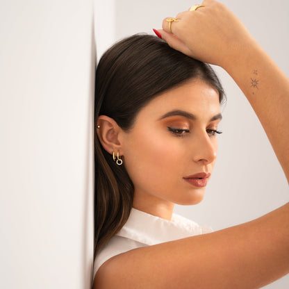 Frau mit goldenen Ohrringen und weißer Bluse, elegantes Schmuckdesign, Modefotografie.