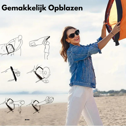 Frau mit aufblasbarem Rucksack am Strand, lächelnd, in Jeansjacke und Sonnenbrille.