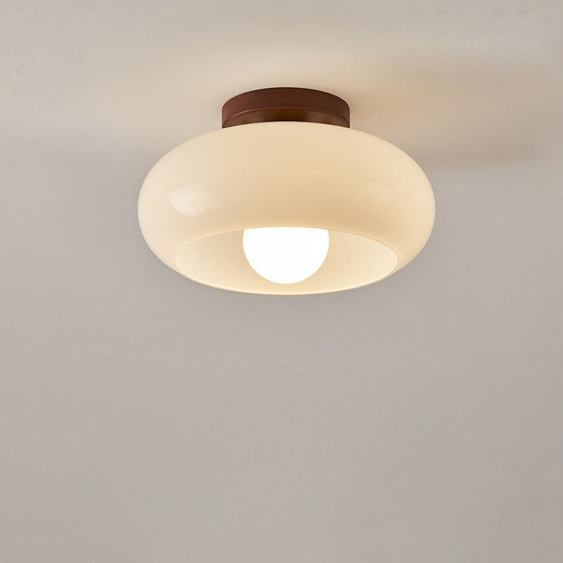Plafond med rund glaskupa och synlig glödlampa, fotograferad rakt framifrån mot grå vägg 6