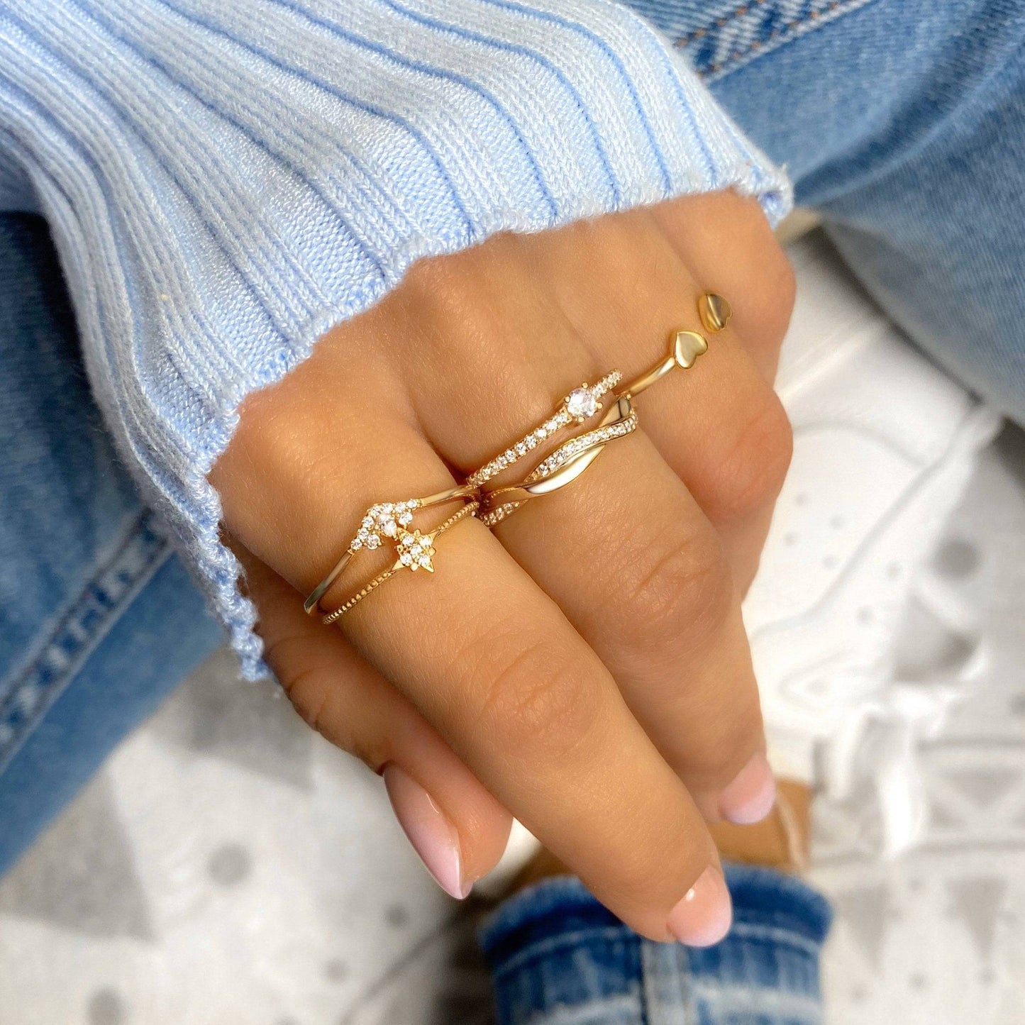 Hand mit goldenen Ringen, Herz- und Stern-Design, Damenmode, Schmuck, Nahaufnahme.