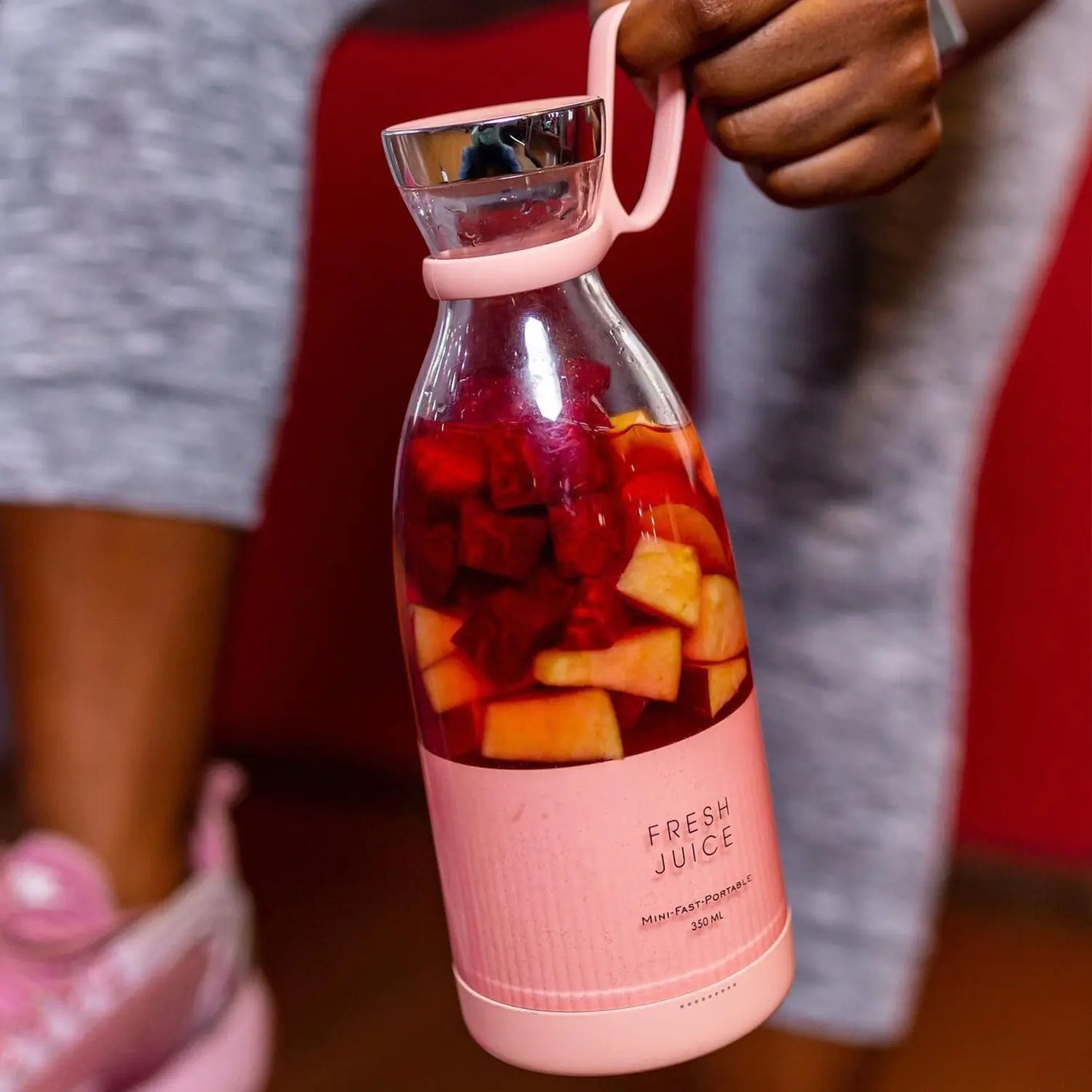 Rosa tragbare Saftpresse mit Obst, ideal für frische Säfte, Fitness, gesunde Ernährung.