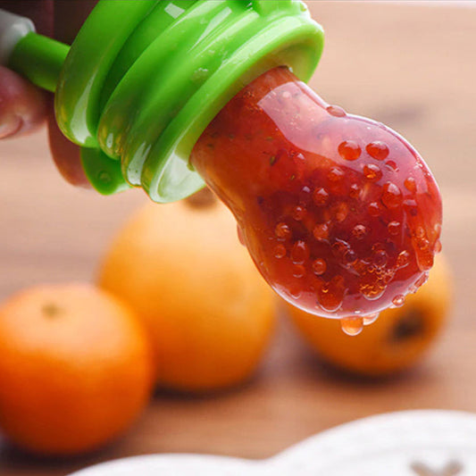 Grüner Baby-Fruchtsauger mit Erdbeeren, BPA-frei, Nahaufnahme, Holzuntergrund.