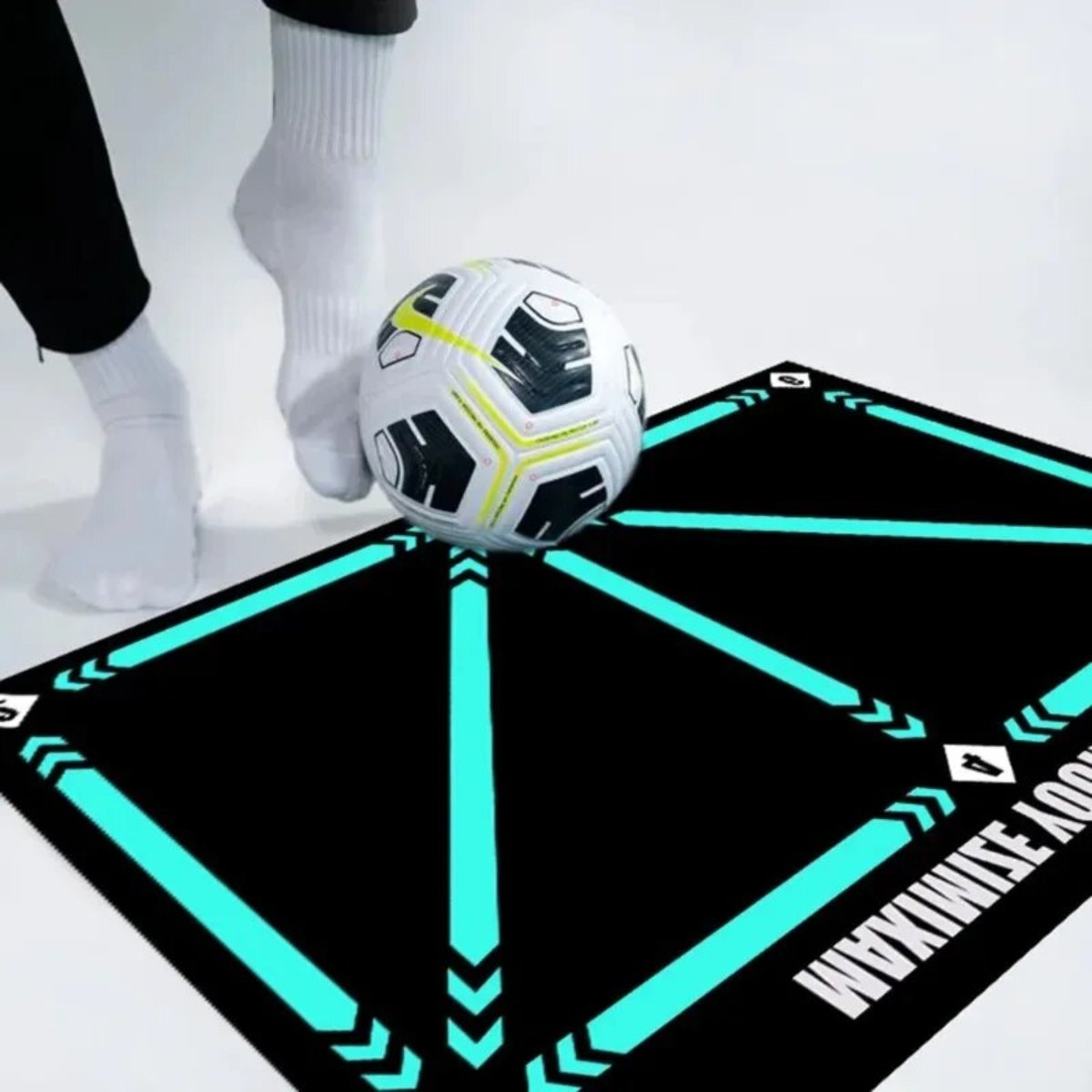 Person spielt mit Fußball auf schwarzer Trainingsmatte mit blauen Linien, Sportausrüstung.