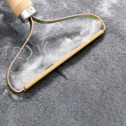 Holzgriff-Fusselentferner auf grauem Stoff, ideal für Wollpflege und Textilreinigung.