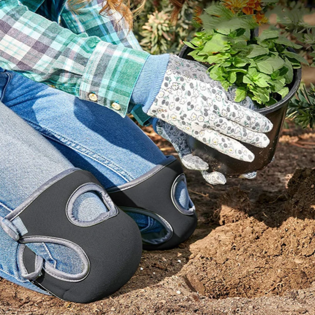 Person pflanzt mit gepolsterten Knieschonern, Gartenhandschuhen und Topfpflanze im Garten.