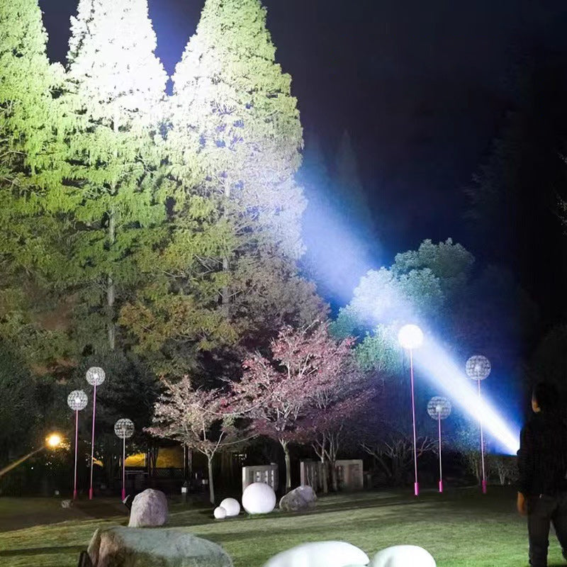 Nachtgarten mit beleuchteten Bäumen und dekorativen Kugelleuchten, stimmungsvolle Außenbeleuchtung.