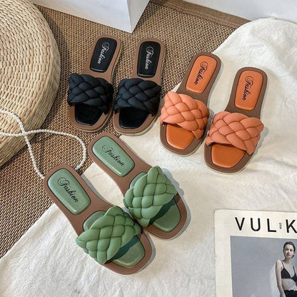 Geflochtene Damen-Sandalen in Schwarz, Orange und Grün auf Teppich, modische Sommerschuhe.
