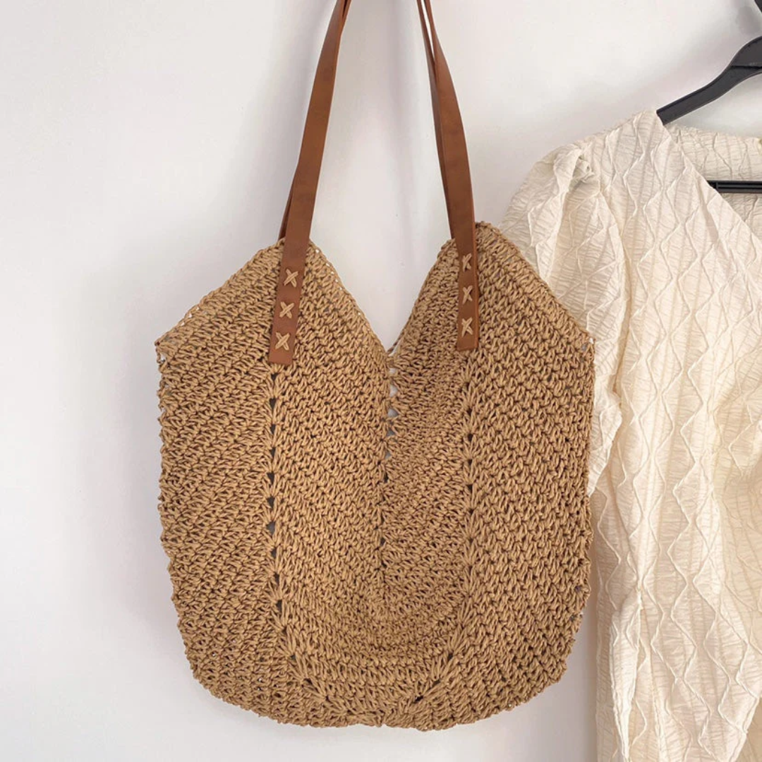 Geflochtene Strohtasche mit braunen Ledergriffen, ideal für Sommer und Strand.