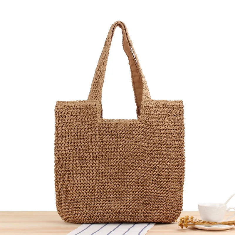Braune handgefertigte Strohtasche auf Holztisch, umweltfreundliche Einkaufstasche.