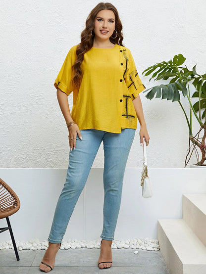 Frau in gelber Bluse und blauer Jeans, steht vor weißer Wand, modisch, lässiger Stil.