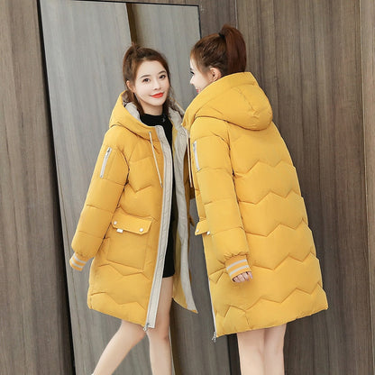 Frau in gelber Daunenjacke mit Kapuze, Wintermode, warm, stilvoll, reflektierender Spiegel.