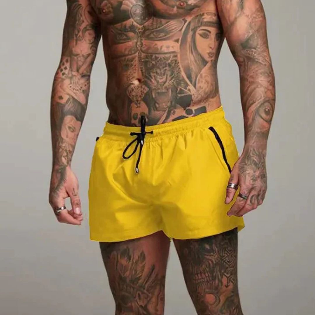 Mann mit Tattoos trägt gelbe Badehose, Sportbekleidung, Sommermode, Herrenmode.