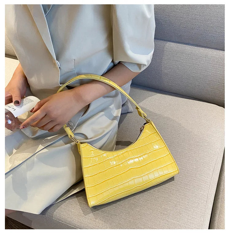Frau mit gelber Croco-Lederhandtasche auf Sofa, elegantes Design, modisches Accessoire.