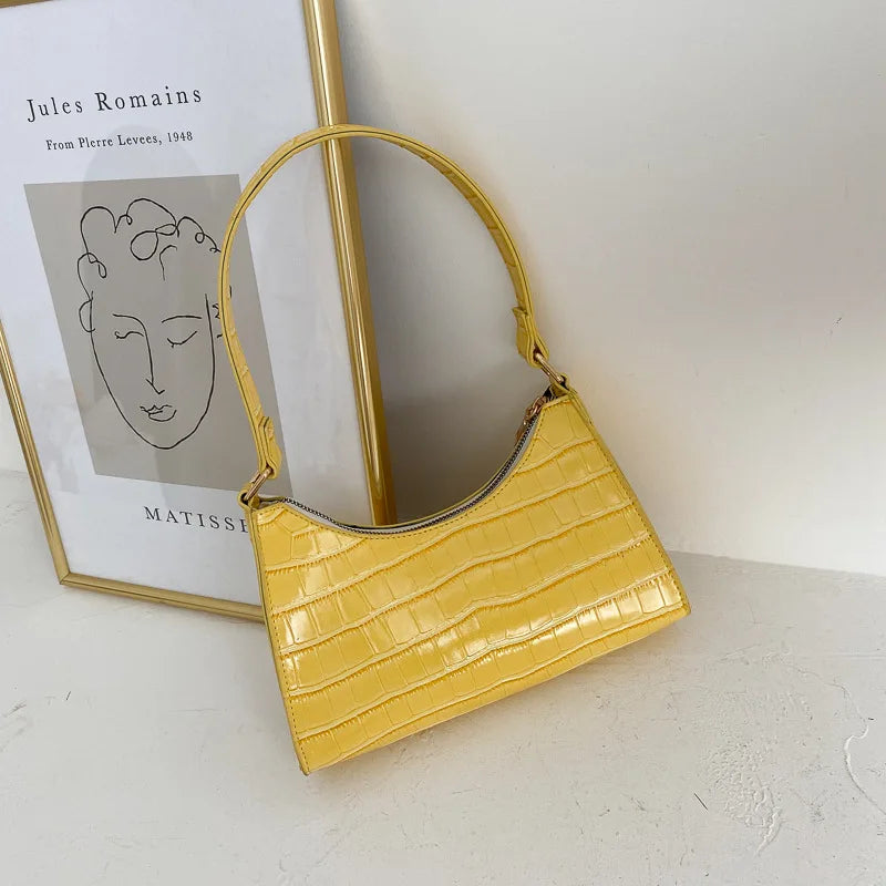 Gelbe Krokodilleder-Handtasche vor Kunstposter, modisches Accessoire, elegantes Design.