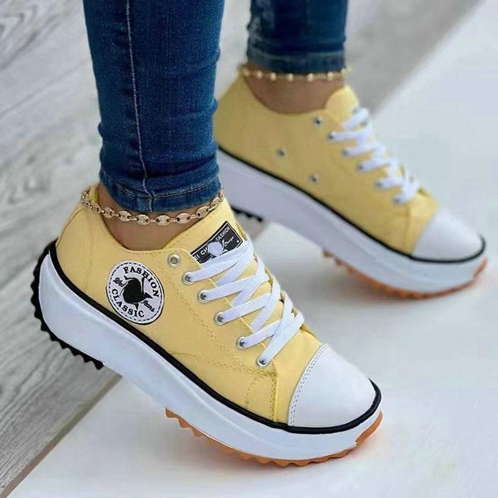 Gelbe Damen-Sneaker mit Plateau, weißer Sohle und schwarzem Logo, modisch und bequem.
