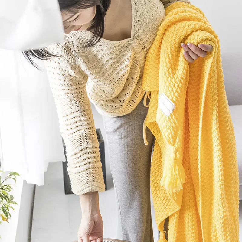 Frau mit gelber Strickdecke, handgefertigt, gemütlich, Wohnzimmer, moderne Inneneinrichtung.