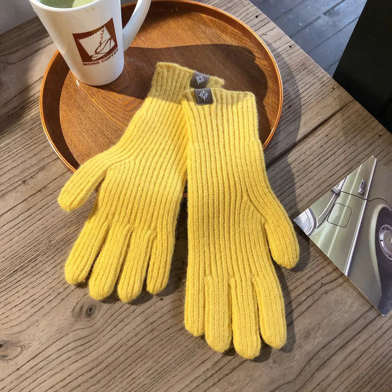 Gelbe Strickhandschuhe aus Wolle auf Holztisch, modisch und warm, ideal für Herbst und Winter.