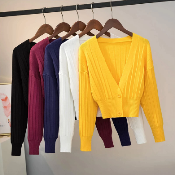 Sechs Strickjacken in Gelb, Weiß, Blau, Rot, Schwarz auf Holzkleiderbügeln im Kleiderschrank.