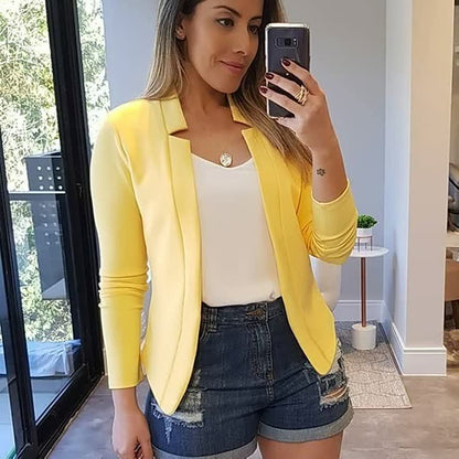 Frau in gelbem Blazer und Jeansshorts, Selfie, modernes Wohnzimmer, modische Freizeitkleidung.
