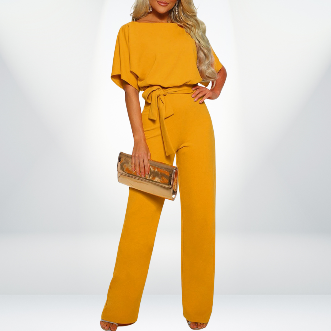 Frau in gelbem Jumpsuit mit Gürtel, hält goldene Clutch, elegante Mode, Abendoutfit.