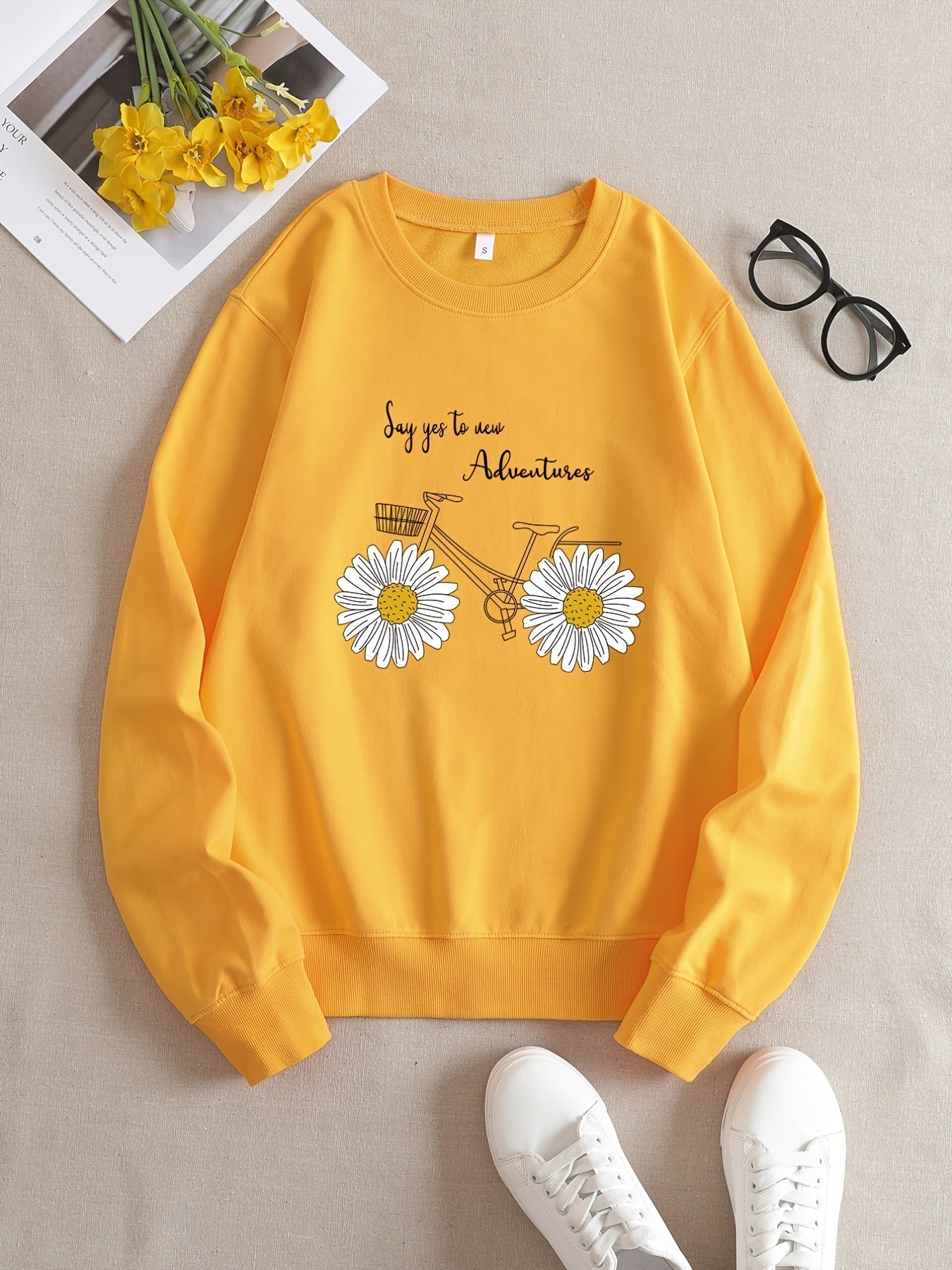 Gelbes Sweatshirt mit Fahrrad- und Gänseblümchen-Design, Text "Say yes to new Adventures".