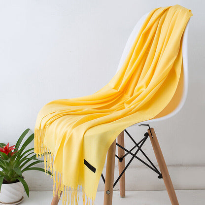 Gelber Kaschmirschal auf weißem Stuhl, weiches Material, modisches Accessoire, Wohnzimmerdeko.