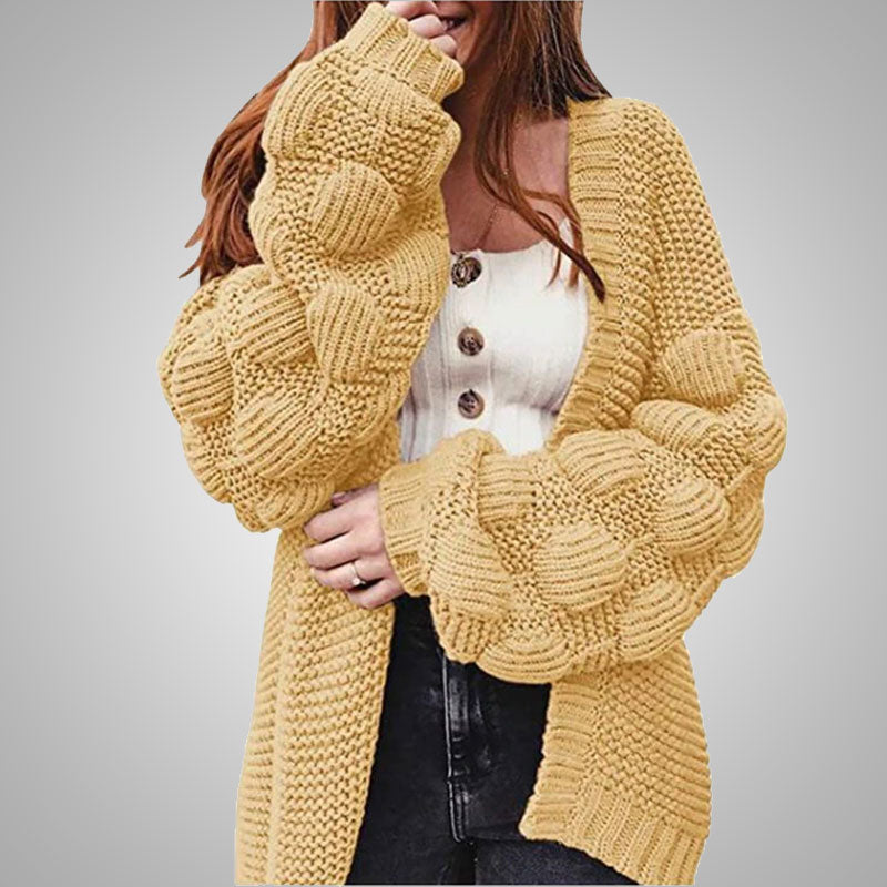 Frau trägt gelbe Strickjacke mit Zopfmuster, weiße Knopfleiste, modisch, gemütlich.