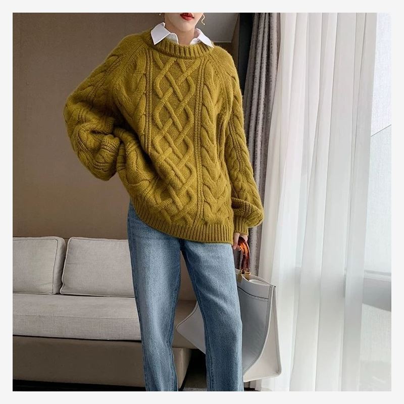 Frau im senfgelben Strickpullover und blauer Jeans, steht in modernem Wohnzimmer.