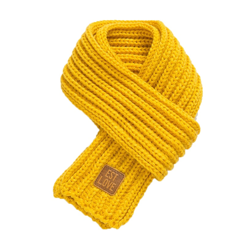 Gelber Strickschal aus Wolle mit Etikett, modisches Accessoire für Herbst und Winter.
