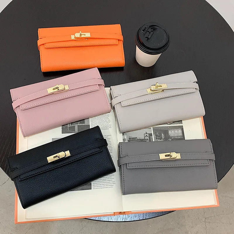 Fünf Lederhandtaschen in verschiedenen Farben auf Tisch mit Kaffeetasse und Buch.