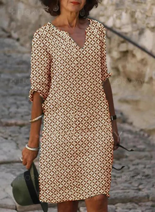 Frau in gemustertem Sommerkleid, braun-weiß, knielang, lässig, modisch, draußen.