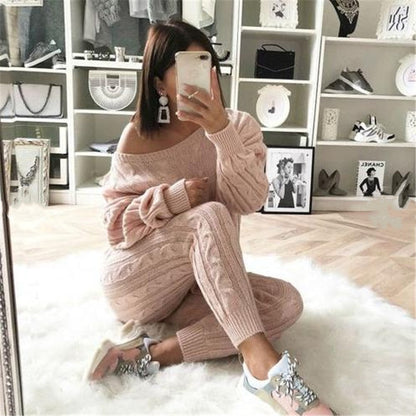 Frau in rosa Strickpullover und Jogginghose, sitzt auf Teppich, modische Sneakers, Spiegel-Selfie.