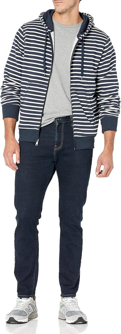 Mann in gestreifter Kapuzenjacke, grauem T-Shirt, dunklen Jeans und Sneakers.