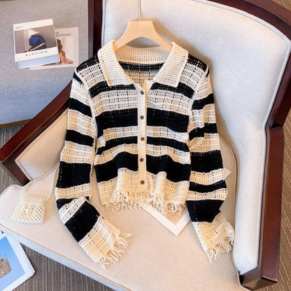 Schwarz-weiß gestreifte Strickjacke mit Fransen, Damenmode, lässig, auf Sessel drapiert.