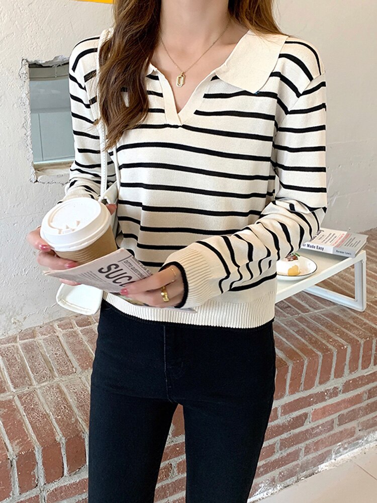 Frau in gestreiftem Pullover mit Kaffeebecher und Zeitschrift, modisch, lässig, schwarz-weiß.