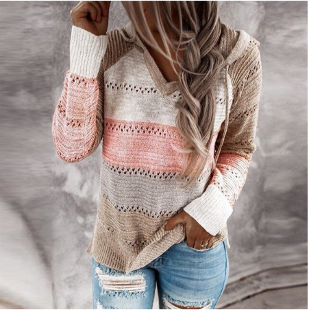 Frau trägt gestreiften Strickpullover in Rosa und Beige, kombiniert mit zerrissenen Jeans.