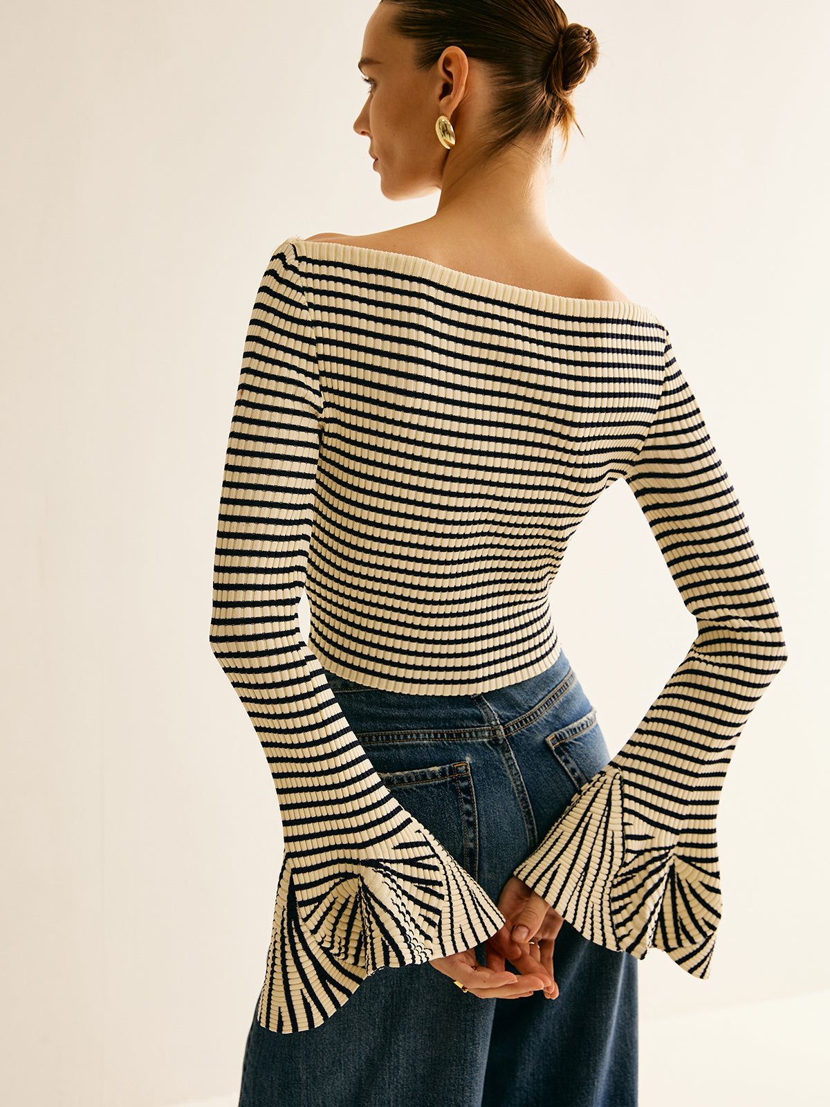 Frau in gestreiftem Pullover mit Trompetenärmeln, blau-weiß, modisch, elegant, Rückansicht.