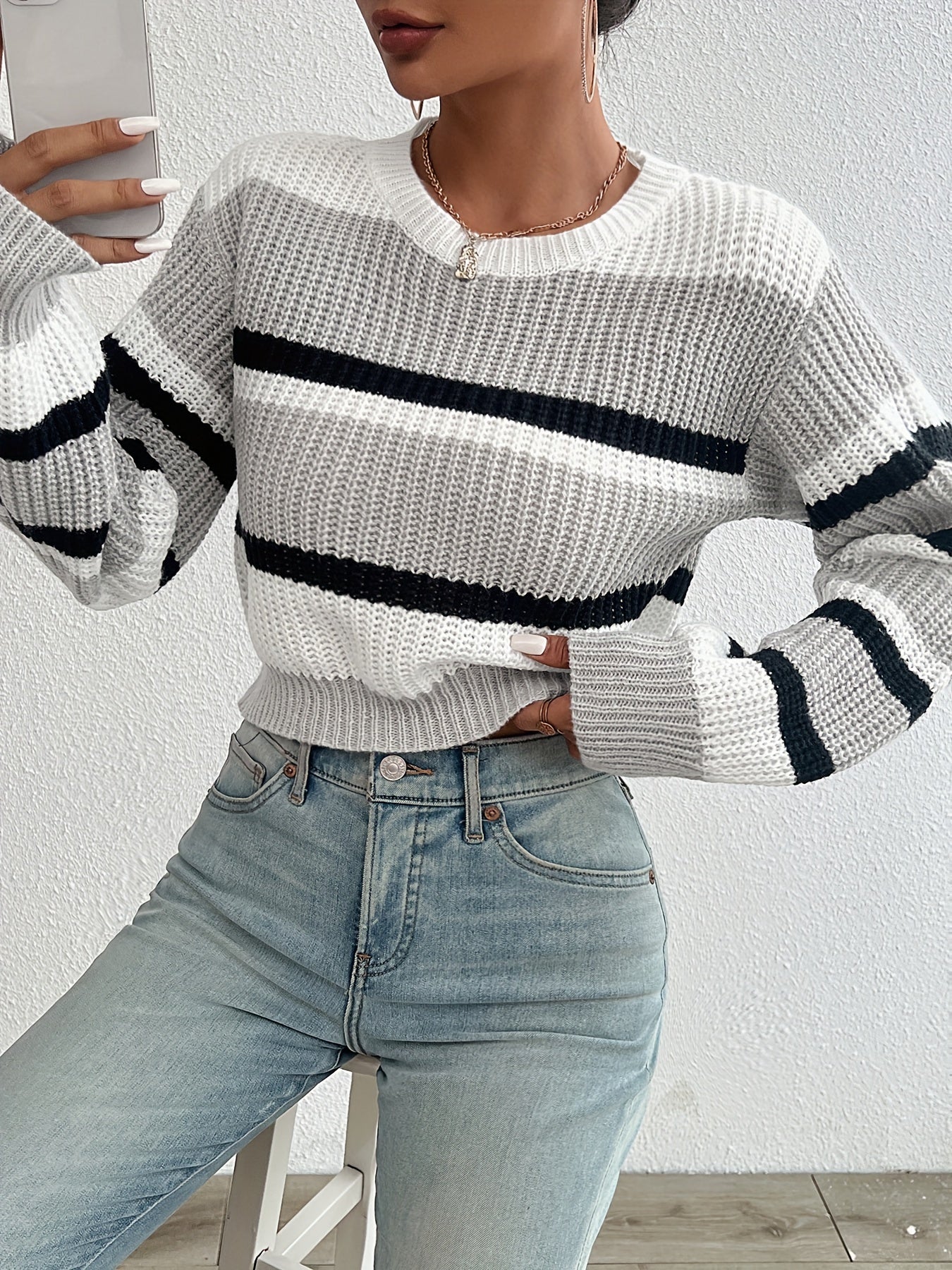 Frau in gestreiftem Strickpullover, weiß-schwarz, mit blauen Jeans, modisch, lässig.