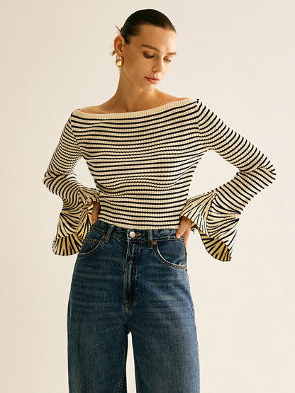 Frau in gestreiftem Langarmshirt und Jeans, modisch, elegant, lässiger Stil, goldene Ohrringe.
