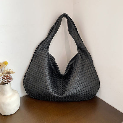 Schwarze geflochtene Handtasche aus Leder auf Holztisch, moderne Damenmode Accessoire.