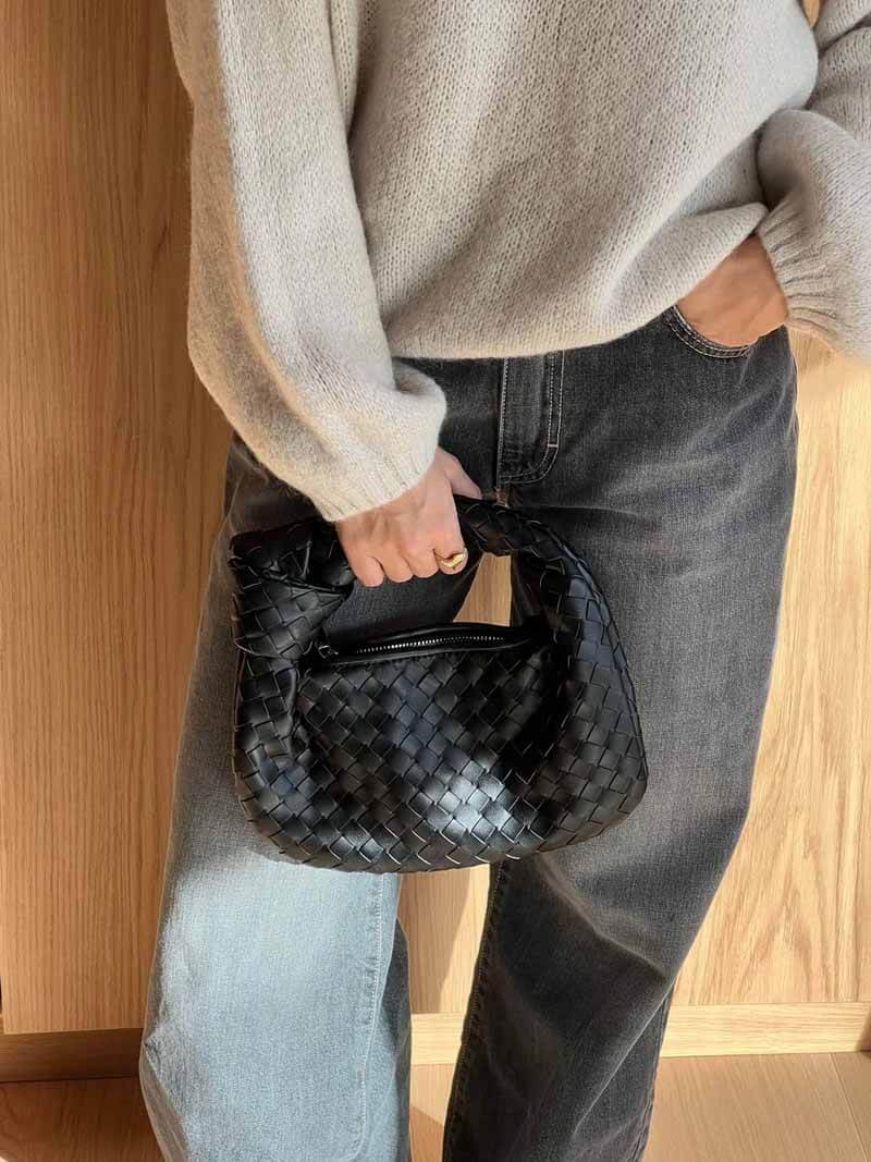 Frau mit schwarzer, geflochtener Ledertasche, lässiger Look, modisches Accessoire.