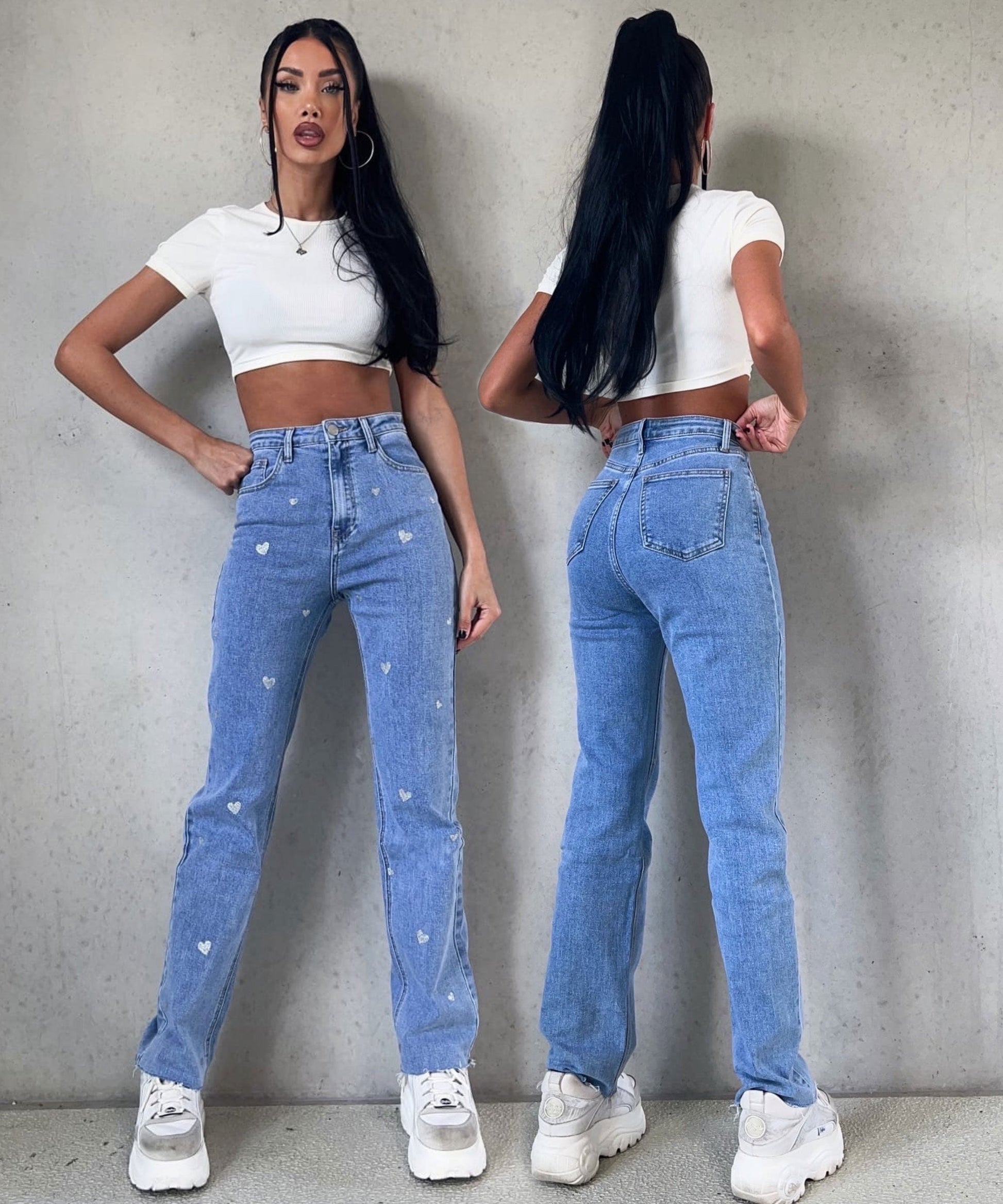 Frau in blauer Jeans mit Herzmuster, weißem Crop-Top, weißen Sneakern, modisch, lässig.
