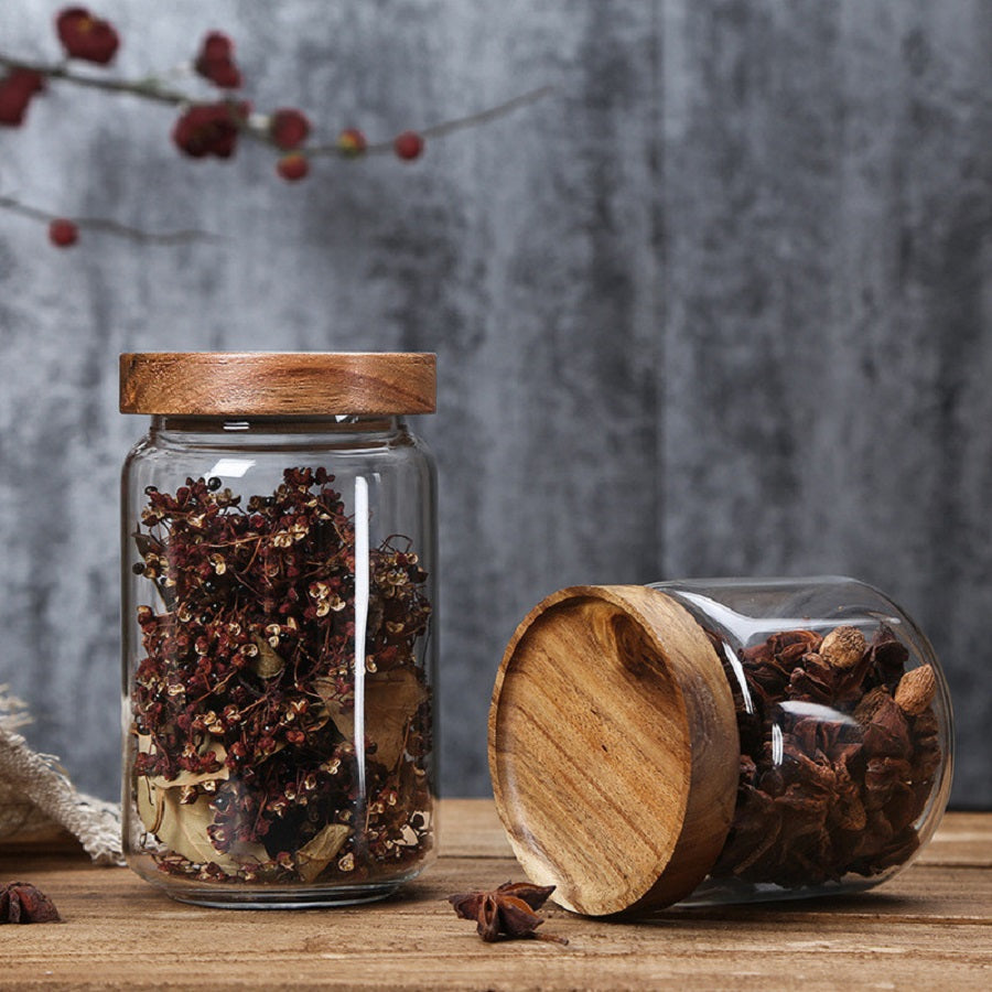 Glasbehälter mit Holzdeckel, gefüllt mit getrockneten Gewürzen, rustikales Küchendekor.