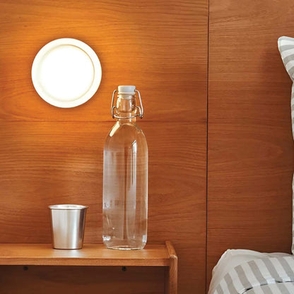 Glasflasche mit Wasser und Metallbecher auf Holzregal, modernes Schlafzimmer, minimalistisch.