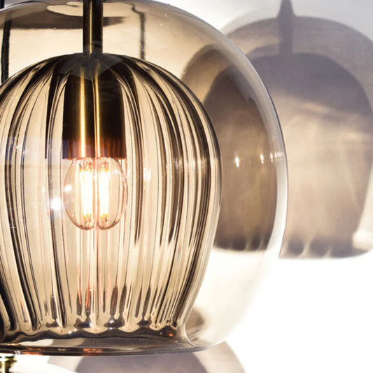 Moderne Hängelampe aus Glas mit Messingdetails, warmes Licht, elegantes Design.