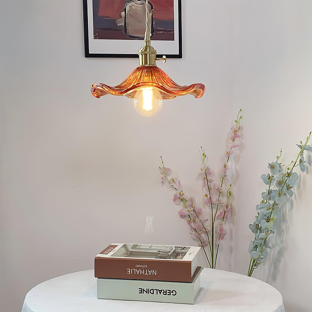Vintage Pendelleuchte aus Glas, orange, über Tisch mit Blumen und Büchern, Retro-Innenbeleuchtung.