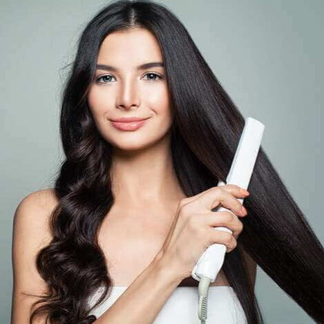 Frau glättet langes, dunkles Haar mit weißem Haarglätter, Haarpflege, Styling-Tool.