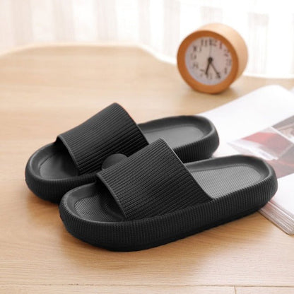 Schwarze Pantoletten aus Gummi auf Holztisch, bequemes Design, ideal für den Sommer.
